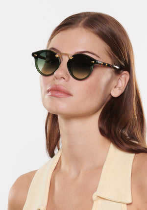 STL NYLON | Bottle Green + Zulu 18K Handcrafted, luxury dark green acetate round KREWE sunglasses with flat edge to edge nylon lens and 18k gold metal bridge womens model | Model: Katie