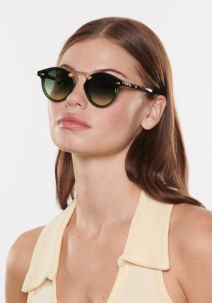 STL NYLON | Bottle Green + Zulu 18K Handcrafted, luxury dark green acetate round KREWE sunglasses with flat edge to edge nylon lens and 18k gold metal bridge womens model | Model: Katie