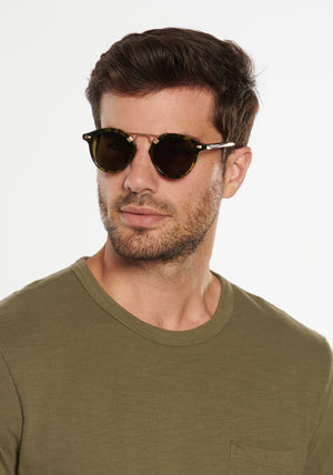 ST. LOUIS | Tortuga 12K Handcrafted, luxury, dark brown black green acetate round KREWE sunglasses with gold bridge and hardware mens model | Model: Douglas